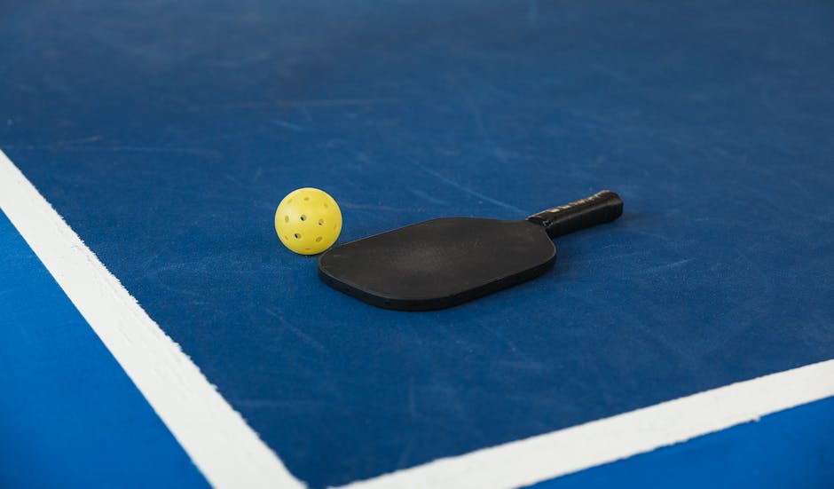 Carbon-fibre faced pickleball paddle close-up showing surface texture and core edge